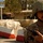 Iraqi Security Force take lead during Ashura movement in Kadhimiyah A soldier in desert camouflage uniform and helmet holds a handheld radio at what appears to be a checkpoint or security post. Concrete barriers painted red and white are visible in the background, along with Arabic script on signage and walls. The setting appears to be an urban Middle Eastern environment, likely Iraq based on the uniform pattern and environmental context.