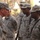 A group of U.S. Army soldiers in ACU (Army Combat Uniform) digital camouflage are gathered in what appears to be an outdoor setting. A senior soldier on the left, whose name tape partially reads 'PEA...' or similar, appears to be engaged in conversation with other soldiers. The setting suggests a military base or operational environment, possibly in a Middle Eastern location based on the lighting and vegetation.