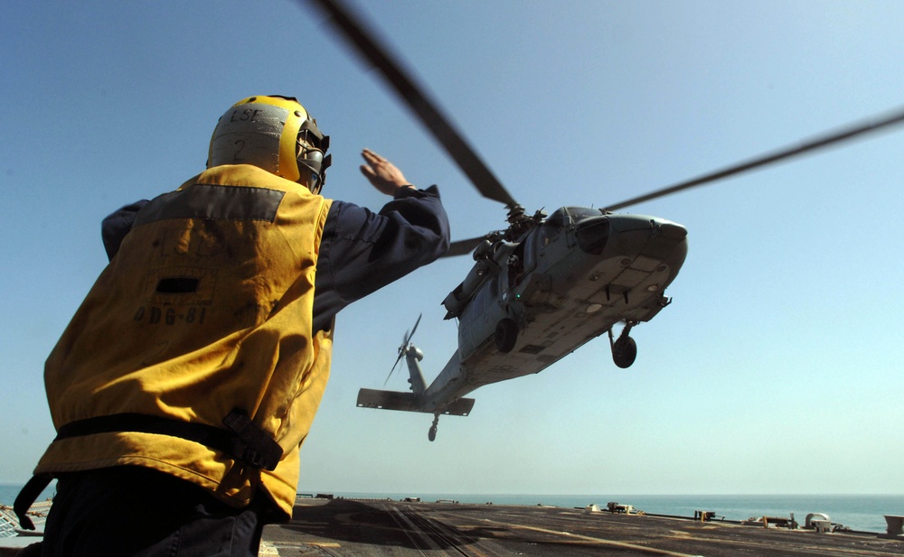 Winston S. Churchill Sailor signals a lifting Seahawk helicopter
