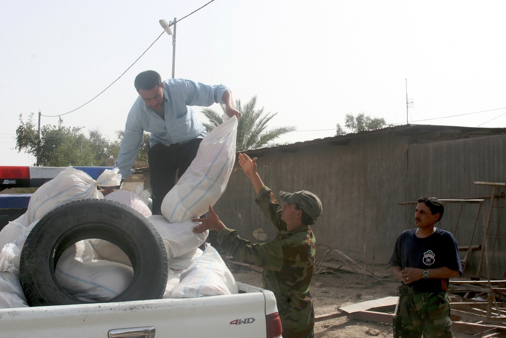 Iraqi policemen provide local needy families with free food bags