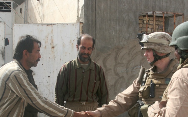 Iraqi policemen provide local needy families with free food bags