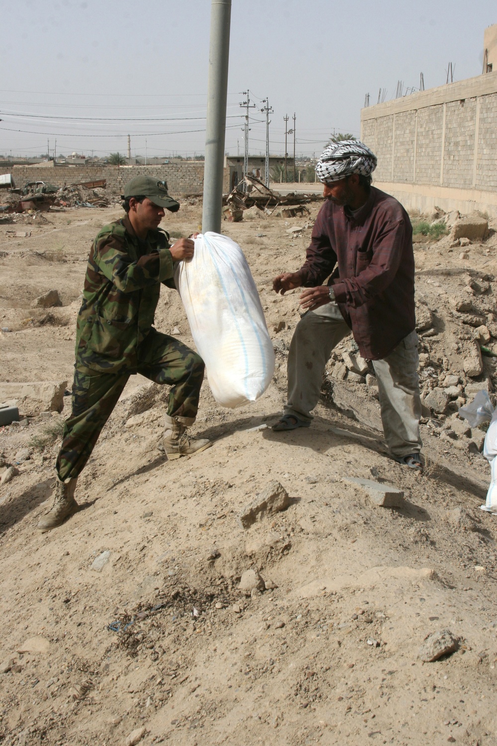 Iraqi policemen provide local needy families with free food bags