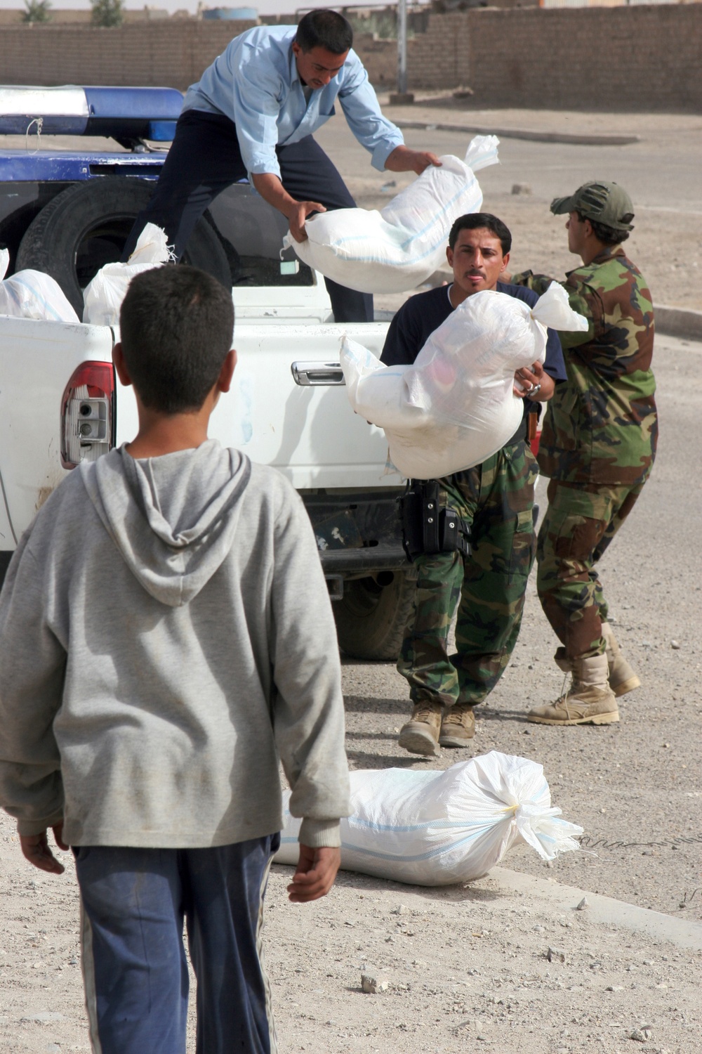 Iraqi policemen provide local needy families with free food bags