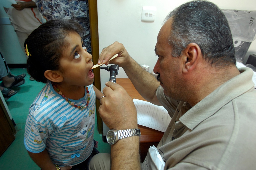 Iraqi doctor examines child's throat during combined medical event