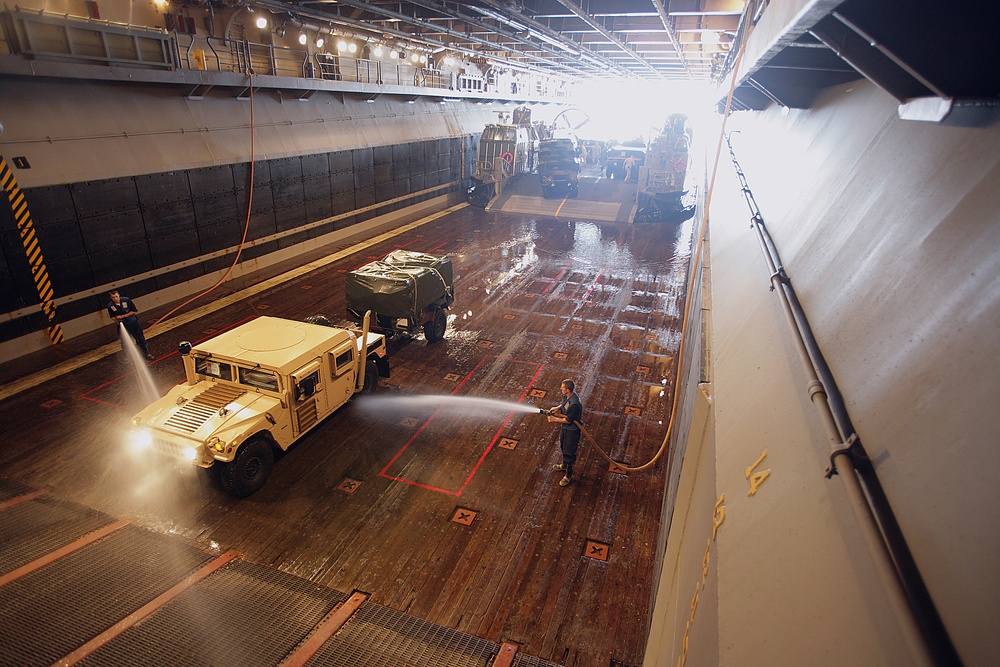 Sailor washes Humvee on USS Iwo Jima Well Deck