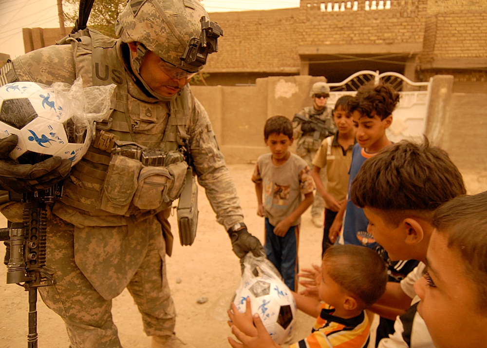 U.S. Soldiers pass out soccer balls