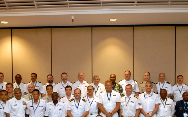 A large group of multinational military and naval officers posed for a formal group photograph in what appears to be a conference or hotel ballroom setting. The attendees are wearing a variety of military dress uniforms from multiple nations, suggesting an international military symposium or conference. Approximately 40 individuals are arranged in four rows for the portrait.