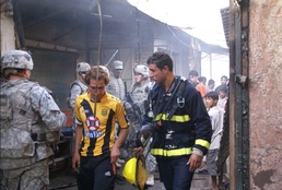 Iraqi Army soldiers secure local fire response teams as they quickly react to a market fire