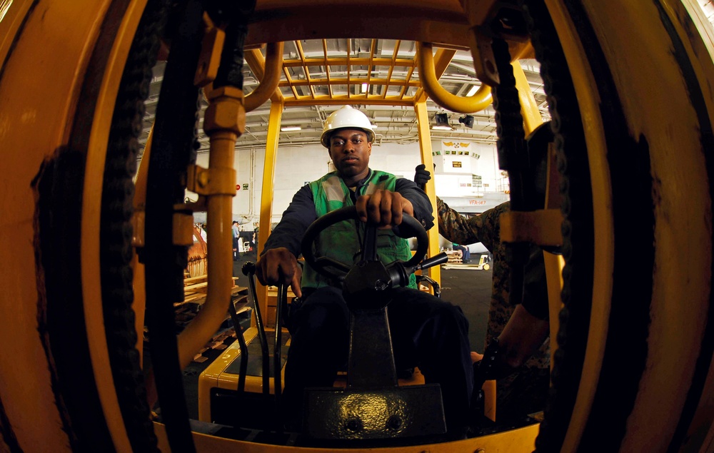 Sailor moves supplies in USS John C. Stennis hangar bay