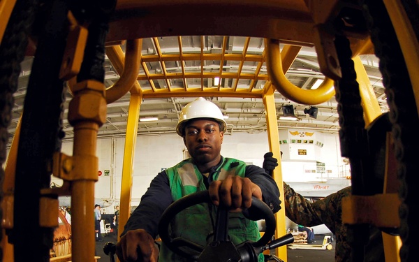 Sailor moves supplies in USS John C. Stennis hangar bay