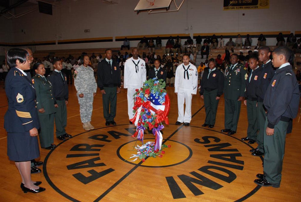 Soldiers, Sailors, Airmen and Junior Reserve Officer Training Corps cadets gather around the roses laid in honor of fallen veterans during the Veterans Day program at Fair Park High School in Shreveport, La., Nov. 11.