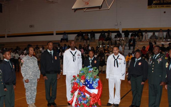 Soldiers, Sailors, Airmen and Junior Reserve Officer Training Corps cadets gather around the roses laid in honor of fallen veterans during the Veterans Day program at Fair Park High School in Shreveport, La., Nov. 11.