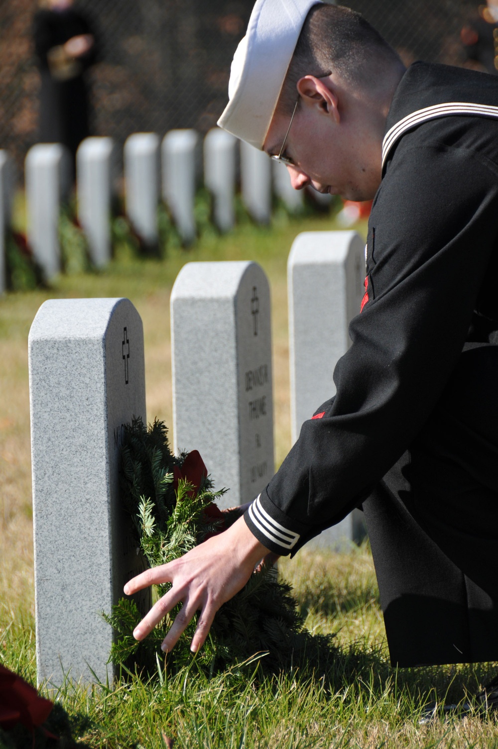 A 2nd class petty officer of the Navy lays a wreath on a fallen Veteran's tombstone during a Wreaths Across America Ceremony at the Alfred G. Horton, Jr. Memorial Veterans Cemetery. Wreaths Across America's mission is to remember the fallen, honor those w