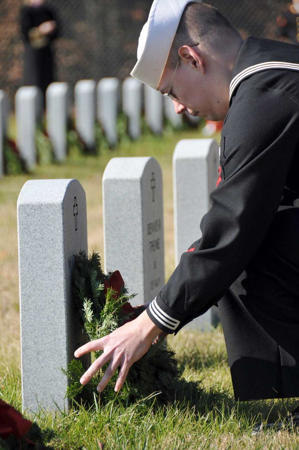 A Sailor lays a wreath on a fallen veteran's tombstone during a Wreaths Across America Ceremony at the Alfred G. Horton, Jr. Memorial Veterans Cemetery. Wreaths Across America is a program to remember the fallen, honor those who serve and teach children t