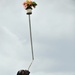 A Uganda Peoples Defense Force Soldier Stands on a Ladder, Balancing a Potted Plant on a Pole in His Mouth, During a Graduation Ceremony at the UPDF Non-Commissioned Officers Academy in Jinja.