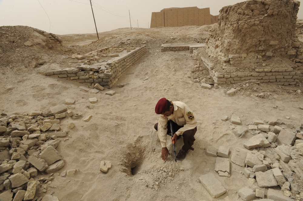 Iraqi security members inspect rocket crater at ancient site
