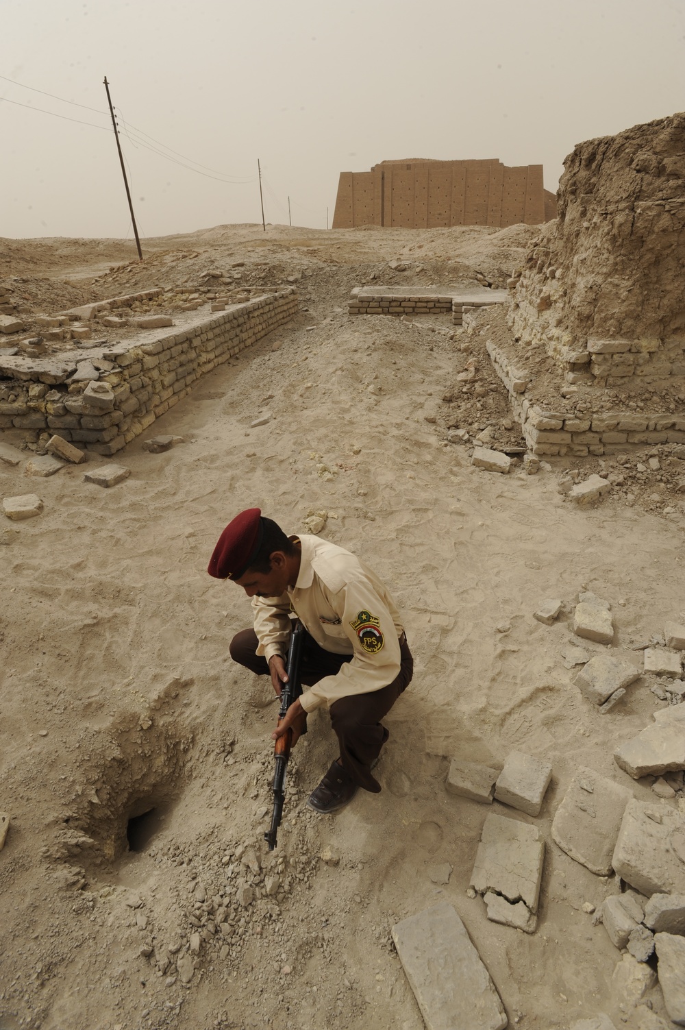 Iraqi security members inspect rocket crater at ancient site