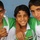Three young boys pose together smiling for the camera, wearing matching white and green sports jerseys featuring the Iraqi flag patch and the PEAK brand logo. They appear to be teammates on a football (soccer) team, with arms around each other in a friendly, celebratory pose. The background is a plain blue wall.