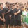 A group of young male football (soccer) players are gathered together, likely during a pre-match ceremony such as a national anthem. Several players in black Nike uniforms have their right hands placed over their hearts, indicating a formal ceremony. Players from multiple teams are visible, wearing black, green, and yellow kits.
