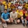 A large group photo taken at what appears to be a soccer/football event, likely in the Middle East based on Arabic text visible on jerseys. The group includes players wearing yellow team jerseys with Arabic script, Barcelona FC jerseys (UNICEF sponsor), and what appear to be military personnel in civilian clothes. Two women are visible among the predominantly male group, one wearing a yellow jersey and another in an orange top.