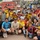 A large group photo taken at a stadium featuring a mix of soccer players in yellow jerseys, civilians, and military personnel in combat uniforms. The gathering appears to be a goodwill soccer event bringing together local players and U.S. military service members, including at least two female soldiers. A 'Fair Play' banner is visible in the background, and the stadium seats are partially filled with spectators.