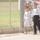 Three young boys are standing near a chain-link fence at what appears to be a football/soccer facility. Two of the boys are wearing white Iraq national football team jerseys, while the third wears a blue and red FC Barcelona-style kit with the number 9 and a UNICEF logo. A large football-themed mural or banner is visible in the background.