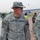 A U.S. Army Major General named Murray is photographed at what appears to be a sports stadium, wearing ACU (Army Combat Uniform) with a boonie hat bearing a single star insignia indicating his rank. He is accompanied by other military personnel and civilians in what appears to be an outdoor athletic facility with a running track and bleachers visible in the background. A flag consistent with the Iraqi flag is visible on a flagpole in the background.