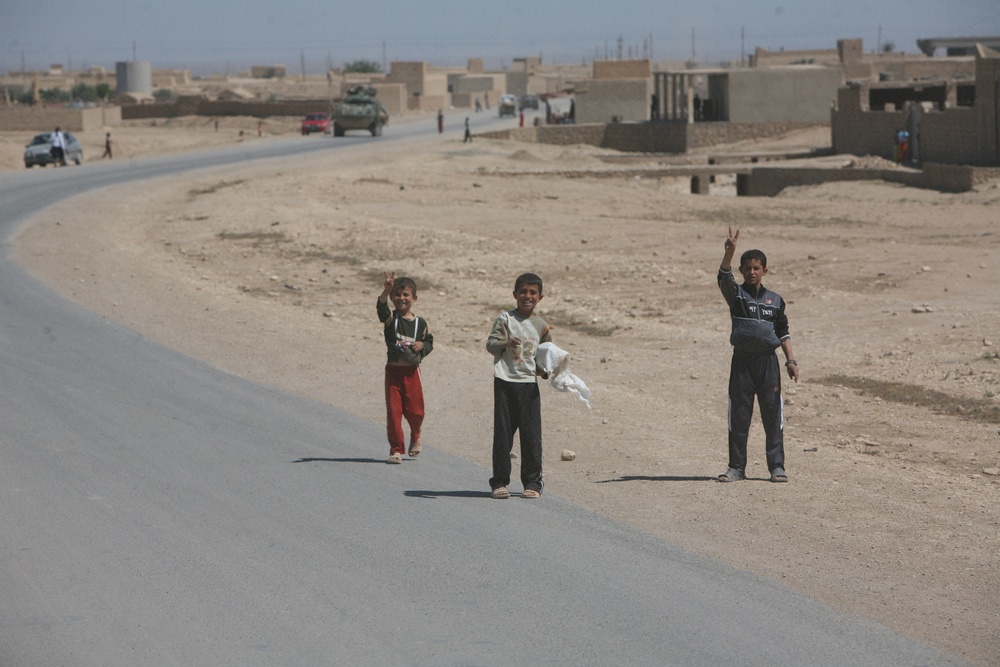 Iraqi children greet passing Marine patrol