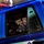 A blue police vehicle is prominently displayed in the foreground, bearing both Arabic script (شرطة) and English 'POLICE' markings on its door. Through the open window, two armed military personnel in camouflage uniforms and helmets are visible, carrying assault rifles. The image appears to document a joint military-police operation or coordination scenario.