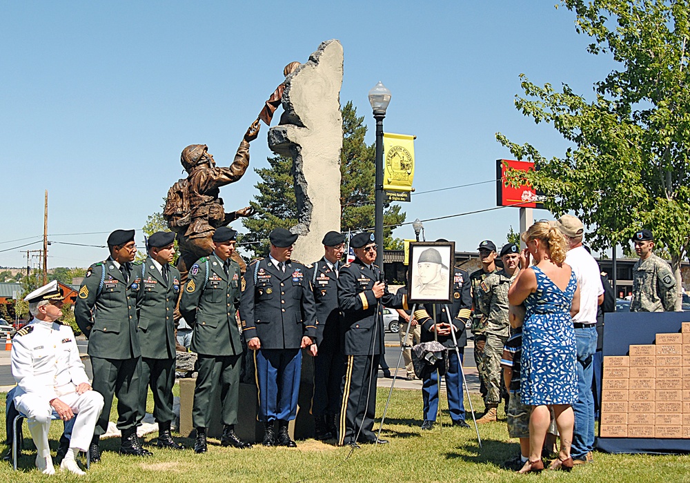 Retired Maj. Gen. Charles Rosenfeld, former Assistant Adjutant General, Oregon Army National Guard, presents a drawing of Pfc. Thomas Tucker to his parents during a dedication of a veteran's memorial in Madras, Ore., Aug. 23. Tucker, was killed in Iraq, J