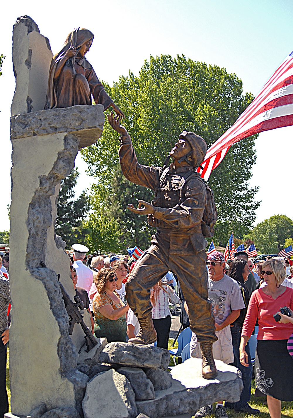 The U.S. Flag flies over a statue of Pfc. Thomas Tucker extending a helping hand to an Iraqi girl in Madras, Ore., Aug. 23. The statue was dedicated as a veteran's memorial in Friendship Park. Tucker, 25, was killed near Baghdad, Iraq, June 16, 2006. The