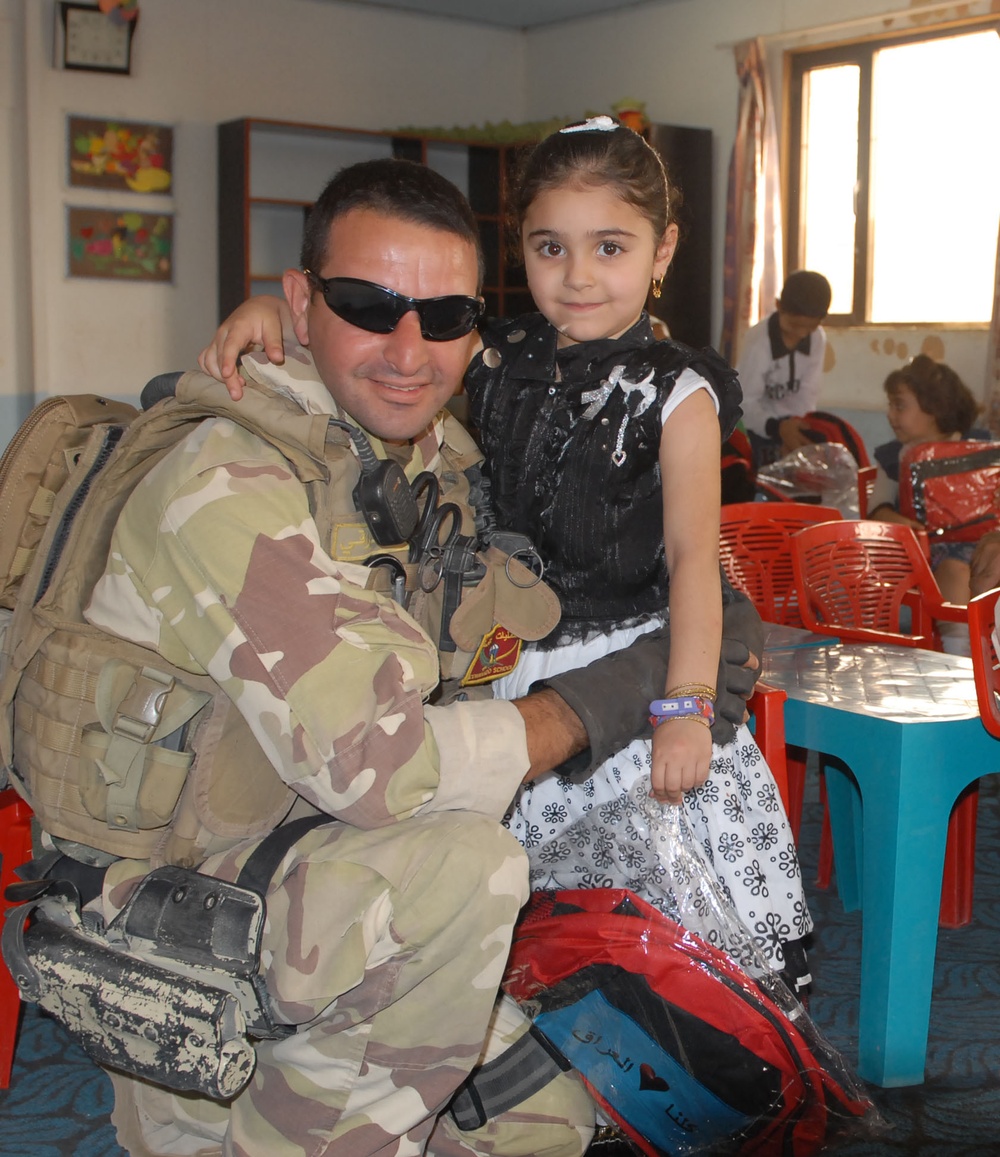 U.S. and Iraqi Soldiers bring backpacks to Baghdad kindergarten