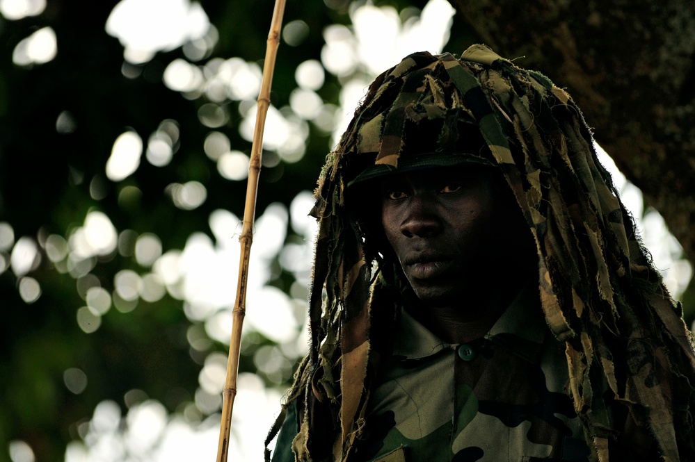 A Uganda Peoples Defense Force soldier stands beneath a tree during a demonstration of skills learned during the UPDF Non-Commissioned Officers Academy in Jinja.