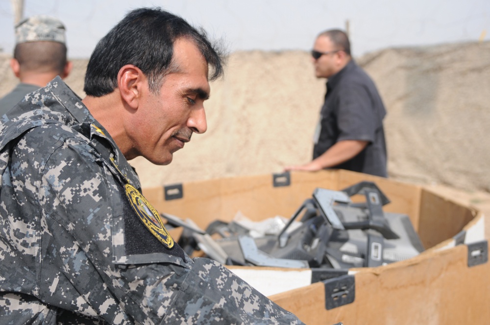 Iraqi policemen sort through equipment for sale, meet with soldiers and airmen
