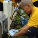 Petty Officer 2nd Class Kristopher Wee, operations specialist, assigned to the guided-missile destroyer USS Chafee, brushes a Navy headstone during a cemetery clean in preparation for Veterans Day. More than 40 Sailors assigned to Chafee and various comma
