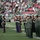 New York Jets Vs Jacksonville Jaguars Military Ceremony Military personnel from multiple branches are standing in formation on an NFL football field, likely during a pre-game or halftime ceremony. The scene takes place at what appears to be a New York Jets home game, identifiable by the Jets logo and green/red stadium seating. Both U.S. Army soldiers in green dress uniforms and U.S. Marines in dress blues are visible among the formations.