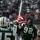 New York Jets Vs Jacksonville Jaguars Military Ceremony A New York Jets NFL player wearing jersey number 92 runs onto the field carrying a large American flag during what appears to be a pre-game ceremony. Other Jets players are visible in the background, including one with 'WRIGHT' and number 15 on their jersey. The stadium is filled with spectators, and cheerleaders are visible in the background.