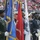 New York Jets Vs Jacksonville Jaguars Military Ceremony A joint military color guard ceremony is taking place at a large sports stadium, with representatives from multiple U.S. armed services branches carrying their respective service flags. The personnel are in formal dress uniforms representing the Army, Marine Corps, Air Force, and Coast Guard, among others. The stadium seating is partially filled with spectators in the background.