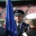New York Jets Vs Jacksonville Jaguars Military Ceremony A military color guard ceremony is taking place at what appears to be a large sports stadium. The central figure is a U.S. Air Force officer in dress uniform holding a blue flag with stars, flanked by personnel from other military branches. The stadium seating is visible in the background with spectators present.