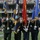 New York Jets Vs Jacksonville Jaguars Military Ceremony A military color guard is presenting flags on the field of an NFL stadium, identifiable as a New York Jets home game based on visible scoreboard and team logo. Multiple branches of the U.S. Armed Forces are represented by service members in their respective dress uniforms carrying branch-specific flags. The stadium is filled with spectators and the scoreboard indicates the first quarter of play.