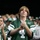 New York Jets Vs Jacksonville Jaguars Military Ceremony A young male fan wearing a New York Jets green jersey with the number 4 stands in a stadium crowd with his hands clasped together. The surrounding crowd, many wearing Jets green apparel and caps, appears to be watching a game. The central subject has a solemn or tense expression, suggesting an emotionally charged moment during the game.