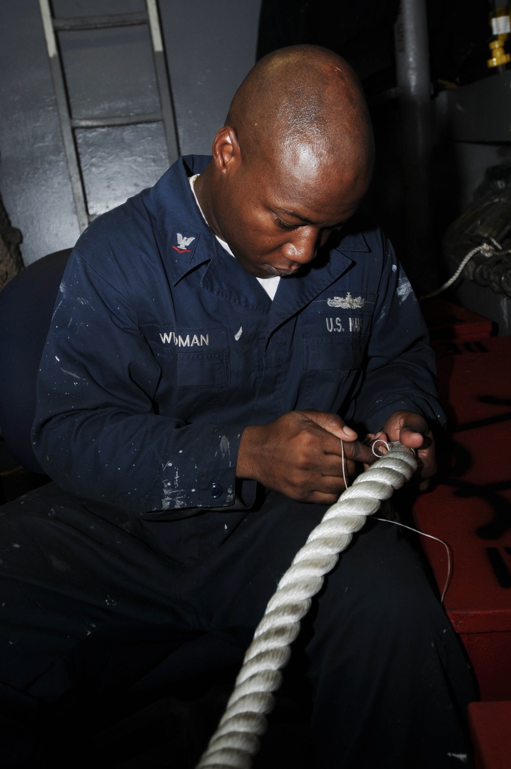 Boatswain's mate performs maintenance on line stopper