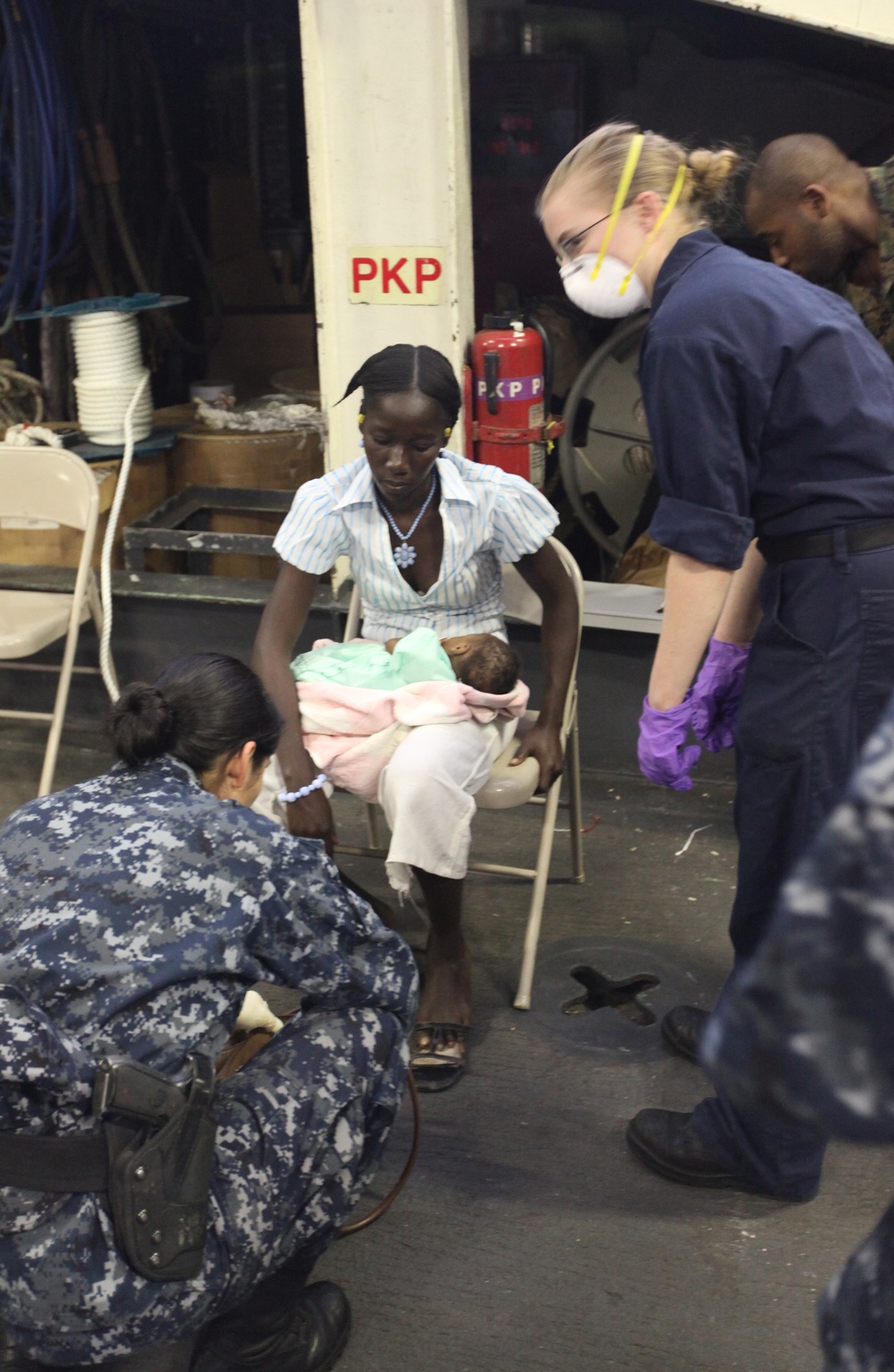 Sailors aboard USS Bataan, attend to a Haitian woman and child during a casualty evacuation