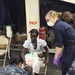 Sailors aboard USS Bataan, attend to a Haitian woman and child during a casualty evacuation