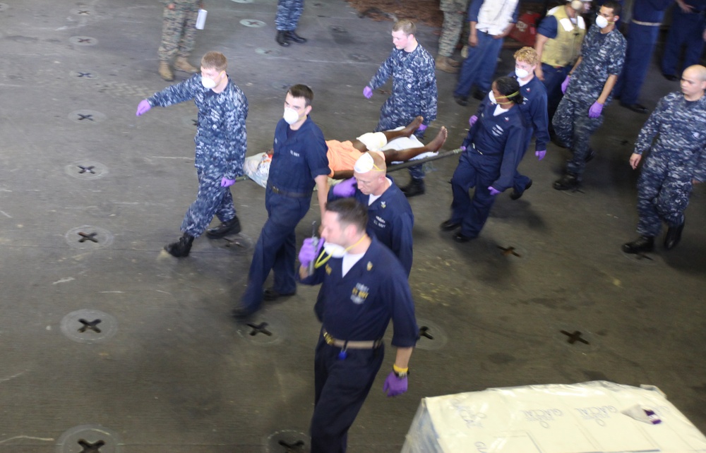 Sailors aboard USS Bataan, attend to a Haitian woman and child during a casualty evacuation