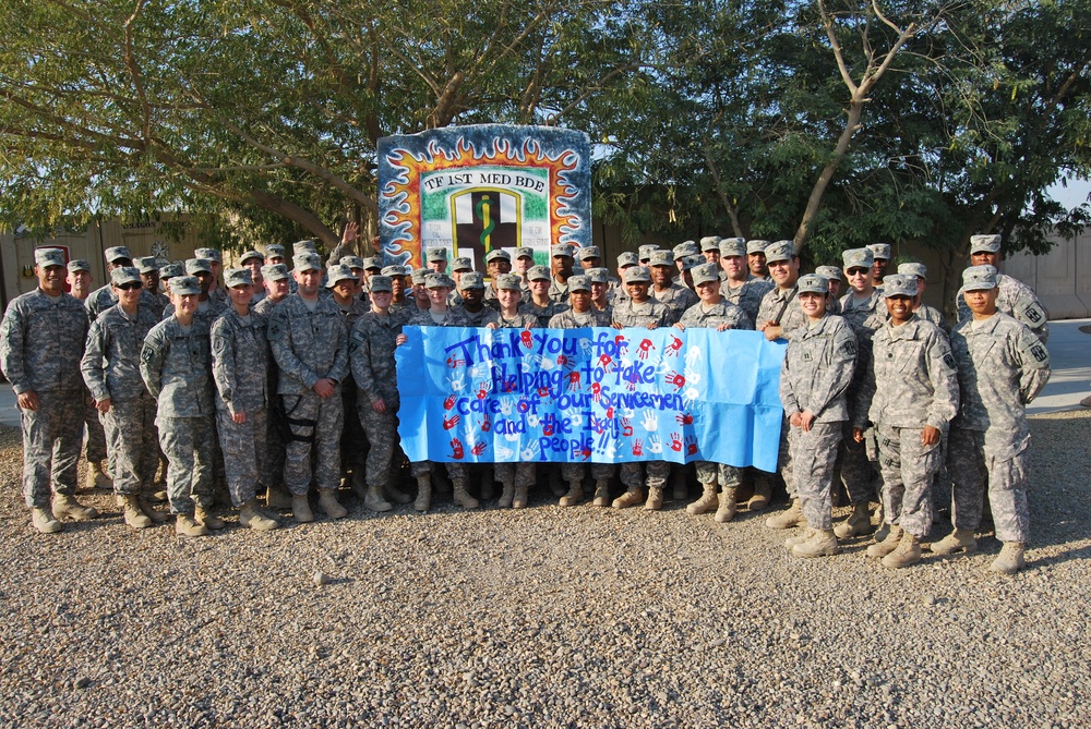 Task Force 1st Medical Brigade Members Pose With a Poster From Sunrise Valley Elementary School