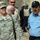 217th Military Police train Iraqi police at the Criminal Justice Center The image shows a U.S. Army Military Police soldier walking alongside a local police officer, likely in a Middle Eastern operational environment. Multiple personnel are visible in the background, including individuals wearing body armor and helmets. The scene appears to depict a joint military-police coordination or patrol activity.