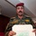 Alaskan MPs run Iraqi Police through tough training A military officer wearing a camouflage uniform with a maroon beret is holding a stack of leaflets or documents featuring Arabic text and an image of a vehicle. The visible Arabic text on the top leaflet references Iraqi security forces and the Iraqi people. The setting appears to be an indoor office or administrative space.