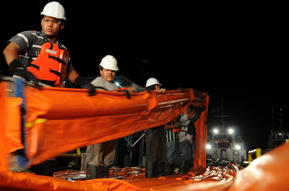 Workers Move Oil Containment Boom Onto a Supply Boat