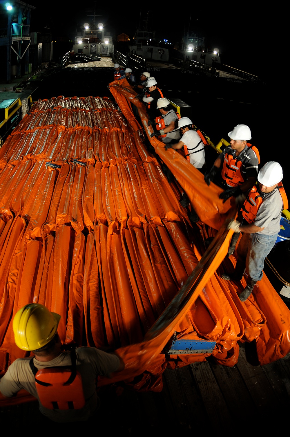 Workers Move Oil Containment Boom Onto a Supply Boat